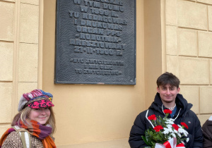 Uczniowie składają kwiaty pod tablicą poświęconą Marszałkowi