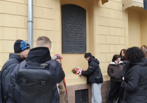 Uczniowie składają kwiaty pod tablicą poświęconą Marszałkowi