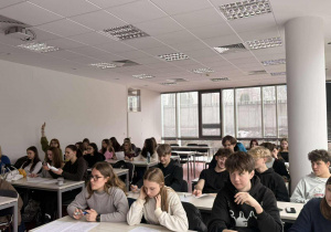 Uczestnicy warsztatów skupieni są na wykonywanych zadaniach – część z nich czyta materiały, inni notują lub rozmawiają cicho z kolegami.