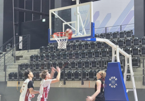 Decydujący moment pod koszem – piłka na obręczy, a zawodnicy gotowi do dobitki w pełnej koncentracji i walce o każdy punkt