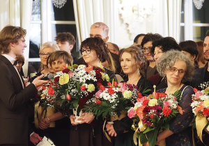 Nauczyciele podczas uroczystej części studniówki odbierają kwiaty i podziękowania od uczniów
