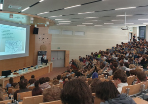 Uczniowie z dużym zainteresowaniem uczestniczą w wykładzie w nowoczesnej auli akademickiej, poznając zagadnienia geograficzne w praktycznym i inspirującym ujęciu.