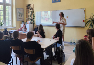 Uczniowie uczestniczą w warsztatach „Erasmus in Schools”, słuchając prezentacji prowadzonej w szkolnej sali.