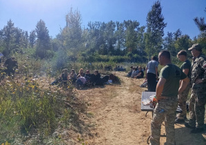 Uczniowie klas pierwszych podczas zajęć survivalowych uczestniczą w odprawie prowadzonej przez instruktorów, przygotowując się do realizacji zadań w terenie.